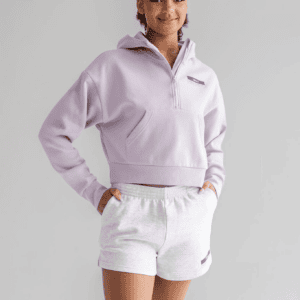 A female dancer is wearing lavender Essentials 3" Fleece Shorts, highlighting the relaxed fit and comfortable design of this dance studio custom apparel.